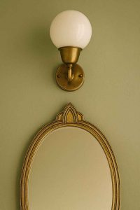 Applique salle de bain vintage en laiton au-dessus d'un miroir art déco
