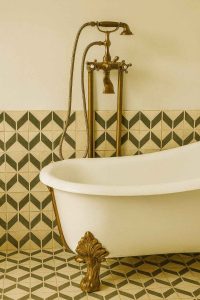 Robinetterie rétro en cuivre et baignoire vintage sur pieds dans salle de bain chic