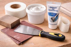 Matériel de bricolage nécessaire pour réparer un mur en placo : enduit, couteau à enduire, bande à joint et papier abrasif