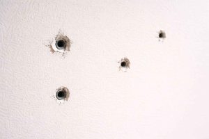 Mur en placo présentant plusieurs petits trous laissés par des clous et des vis avant réparation