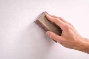 Ponçage d'un mur en placo après rebouchage pour obtenir une surface parfaitement lisse avant peinture