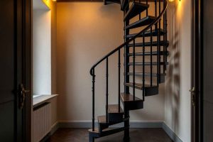 Escalier hélicoïdal en colimaçon en fer forgé noir dans un petit appartement. Solution idéale pour gagner de la place au sol tout en apportant une touche de design à un espace réduit