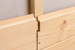 Détail d'un assemblage de lambris en bois, illustrant la technique de pose avec rainure et languette