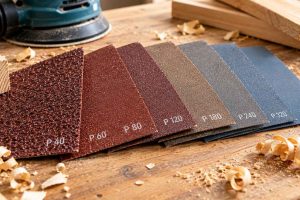 Gros plan sur différents grains de papier abrasif, illustrant les outils nécessaires pour le ponçage